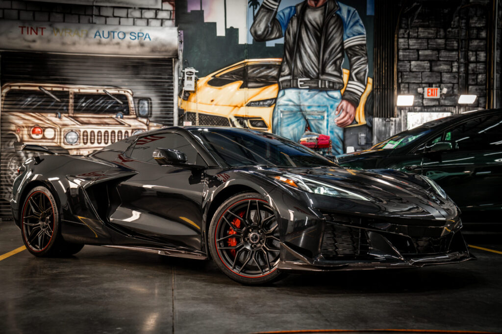 Black Corvette inside the Tinterz install bay against a graffiti mural